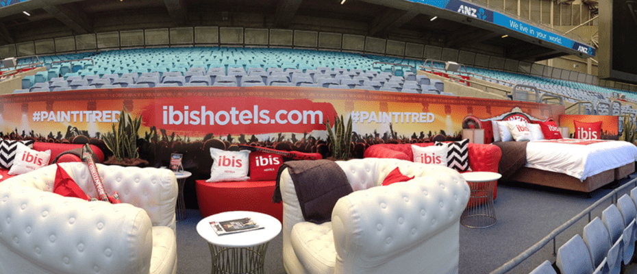 Wide angle view of the bed and cushions with the ibis hotel logo on them
