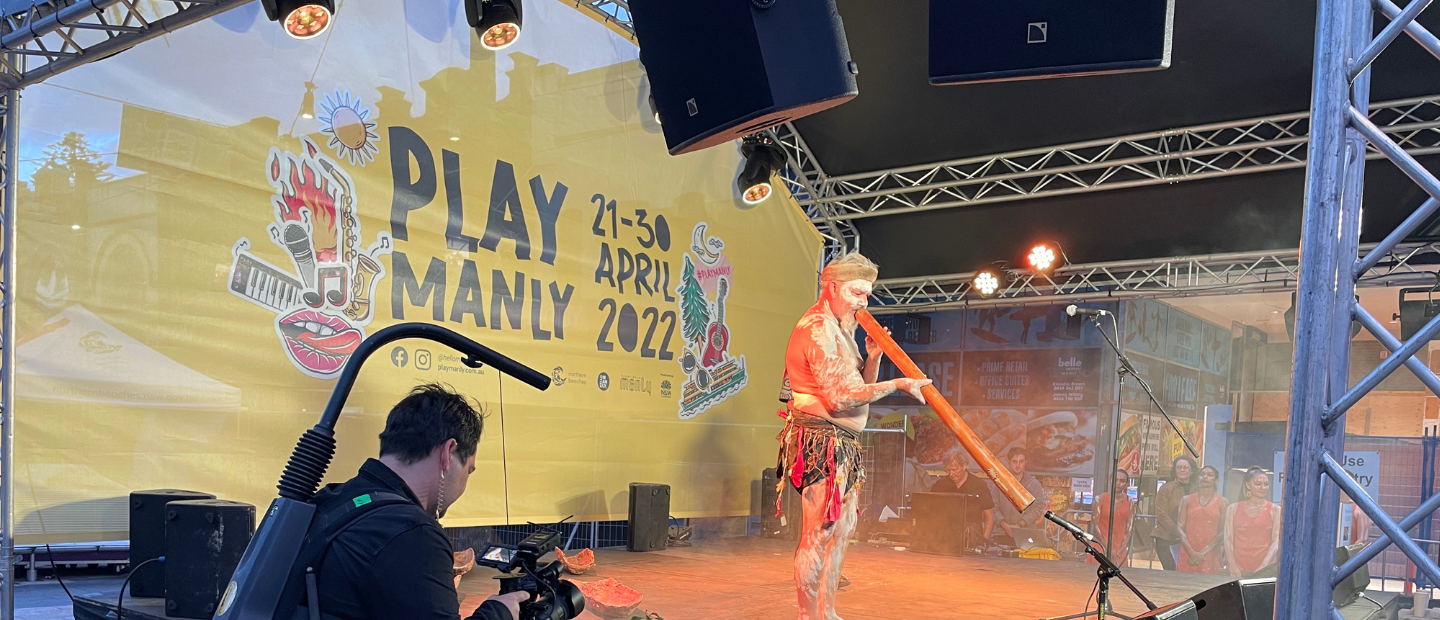 A man playing music using a traditional wooden instrument during play manly project